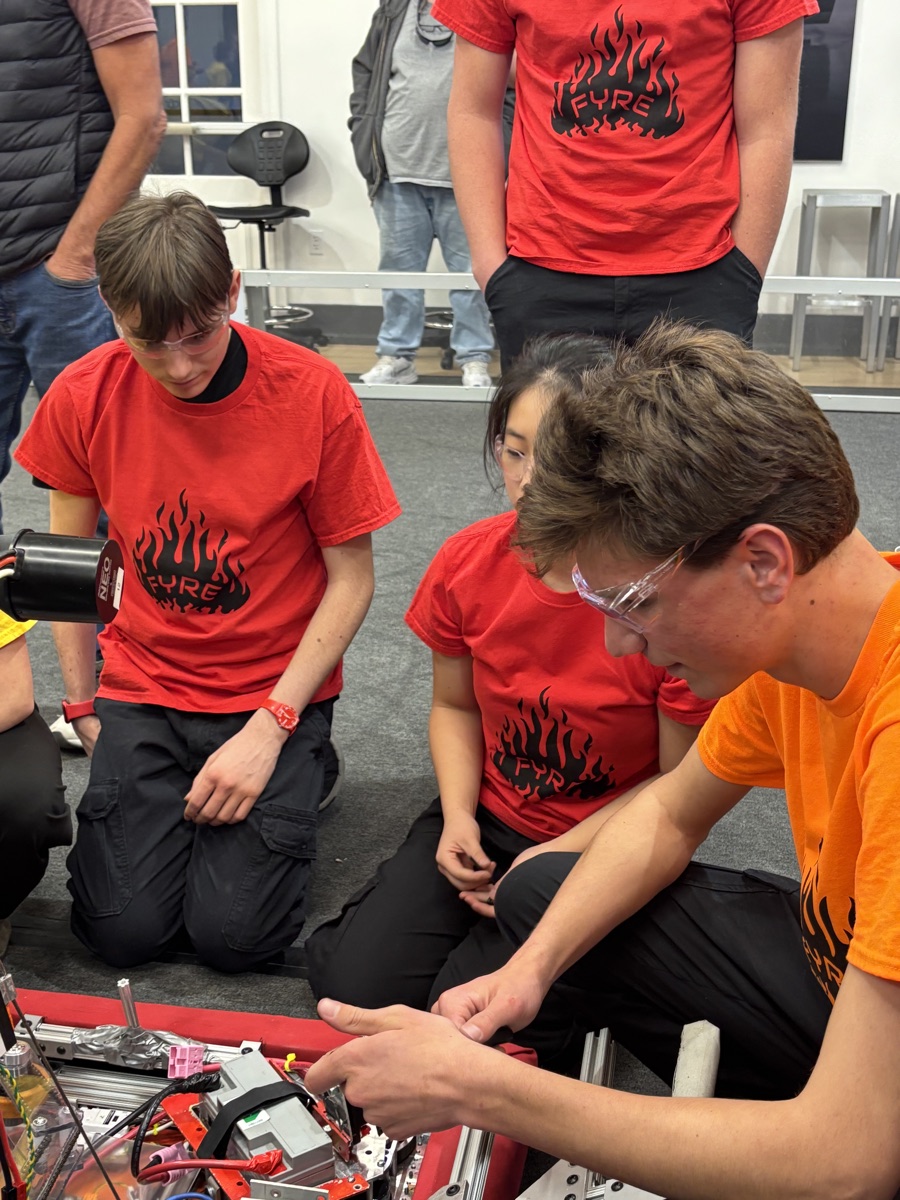 Etienne working on the robot's wiring with teammates